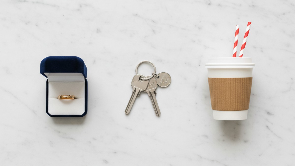 Flat-lay of a wedding ring, apartment keys, and coffee cup representing different relationship types